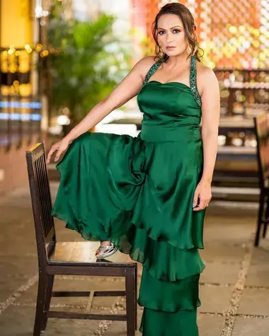 अशिता धवन हरे रंग के कपडे पहनकर एक पैर कुर्सी पर रखकर खड़ी हुई है